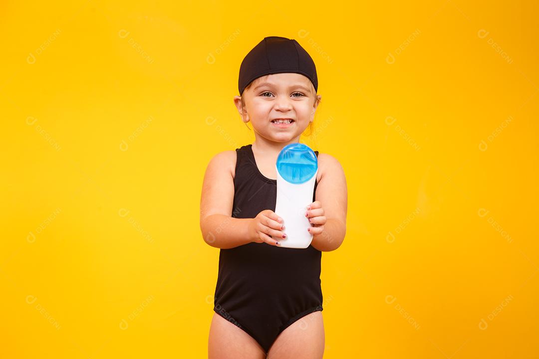 Menina com maiô de natação e protetor solar.