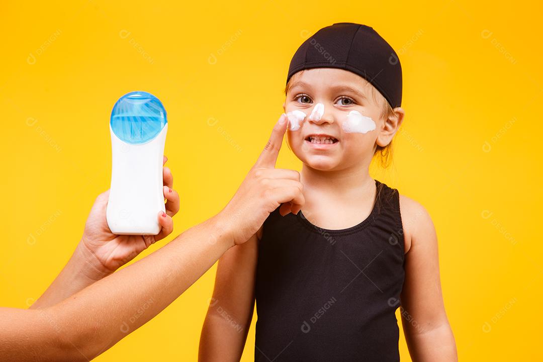 Menina com maiô de natação e protetor solar.