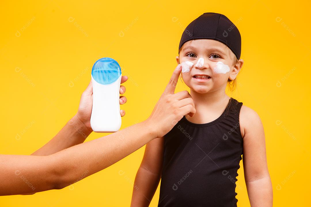 Menina com maiô de natação e protetor solar.