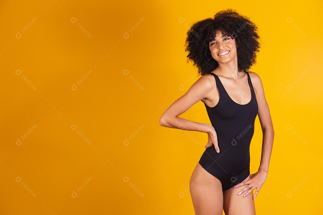 Mulher bonita com cabelo afro em traje de banho em fundo amarelo