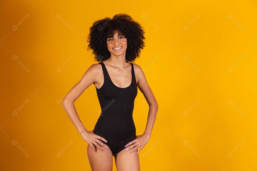 Mulher bonita com cabelo afro em traje de banho em fundo amarelo