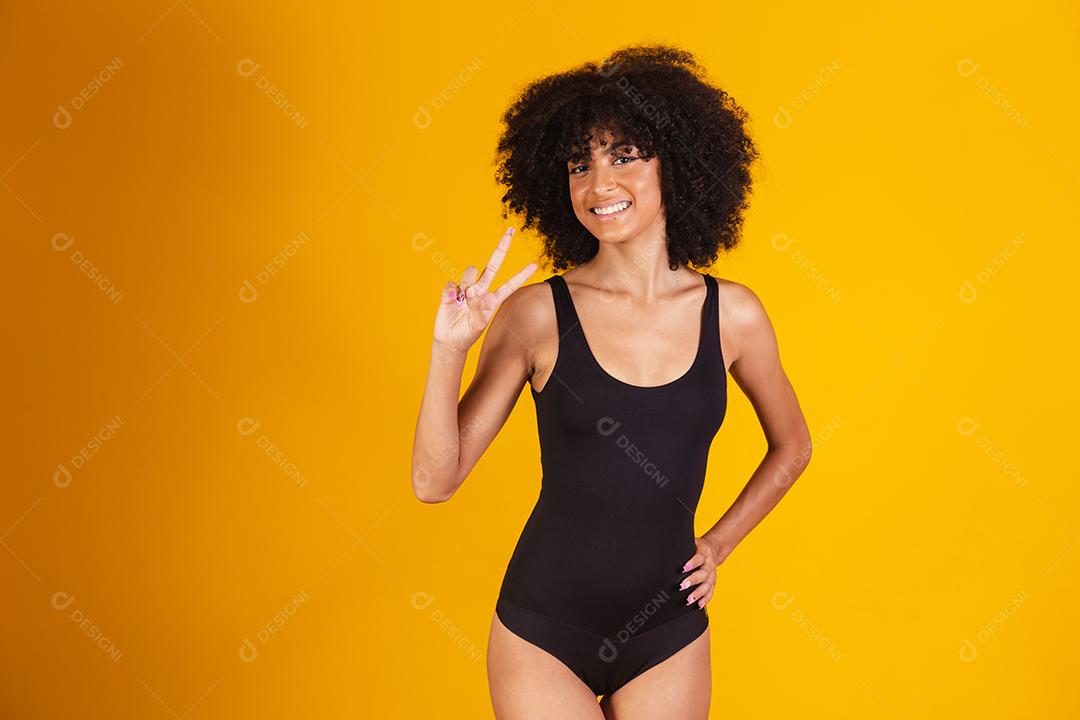 mulher afro fazendo sinal de V com as mãos. Garota afro feliz com boa vibração fazendo paz e amor com as mãos