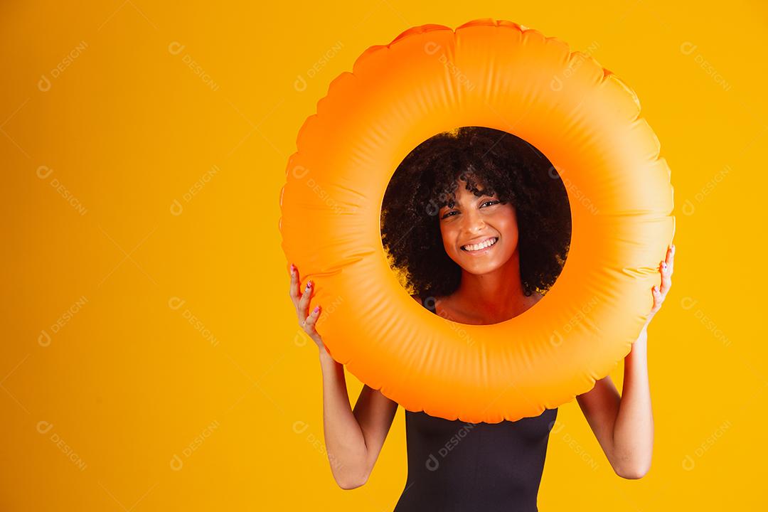 Linda mulher afro segurando lifebuoy em fundo amarelo. mulher com boia flutuante