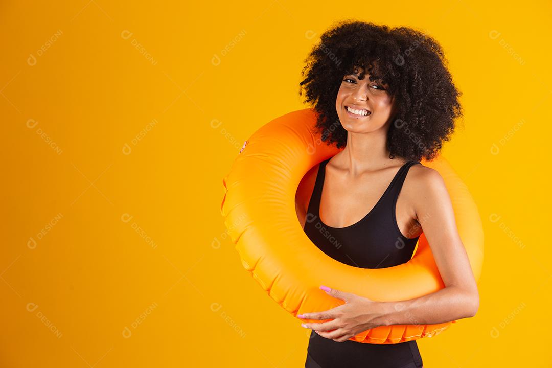 Linda mulher afro segurando lifebuoy em fundo amarelo. mulher com boia flutuante