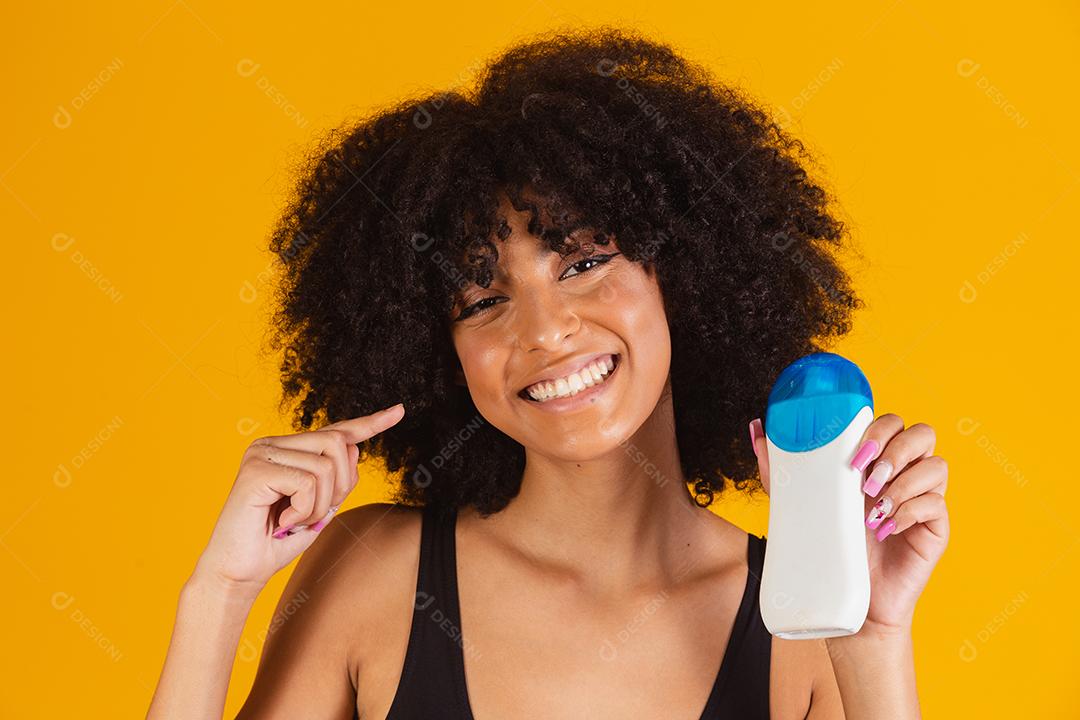 Mulher afro segurando um protetor solar na mão