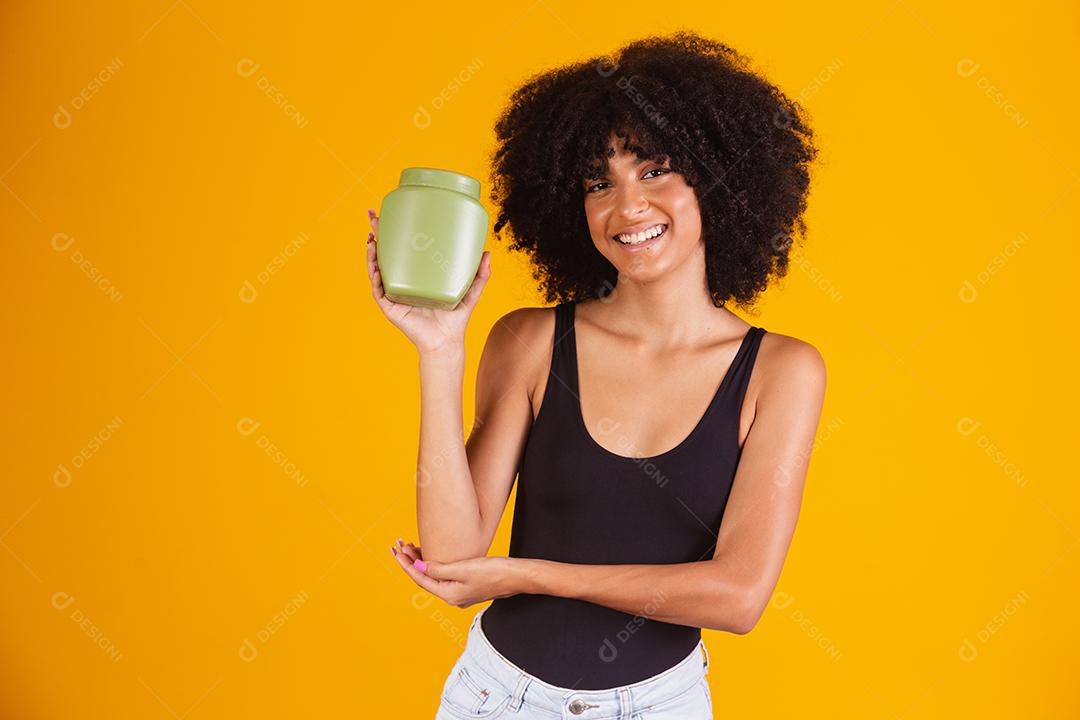 jovem afro segurando nas mãos um pacote de creme de cabelo