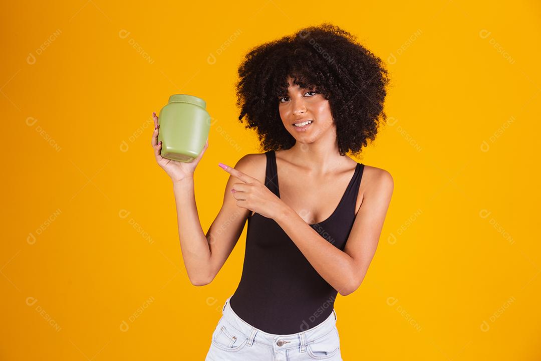 jovem afro segurando nas mãos um pacote de creme de cabelo