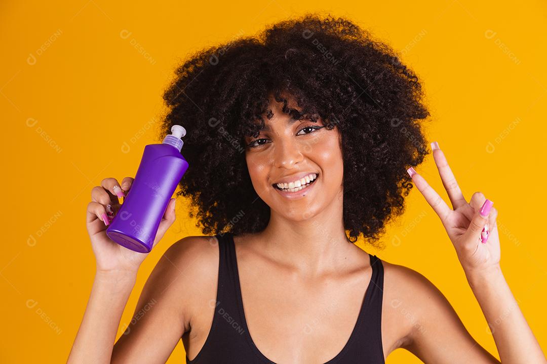 jovem afro segurando nas mãos um pacote de creme de cabelo