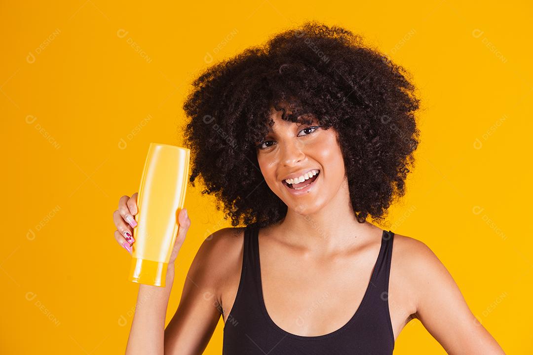 young afro woman holding a pack of hair cream in her hands