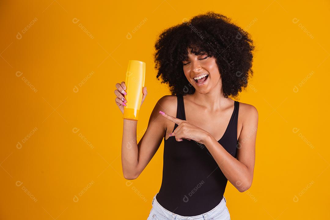 jovem afro segurando nas mãos um pacote de creme de cabelo