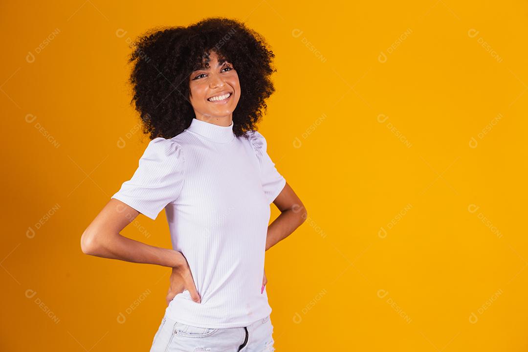 Mulher afro com lindo cabelo preto sorrindo em fundo amarelo