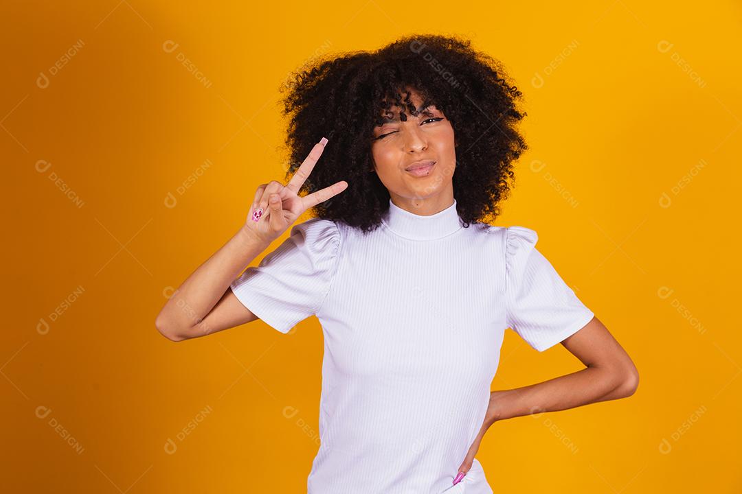 Jovem linda mulher afro-americana com cabelos cacheados, vestindo camiseta casual em pé sorrindo para a câmera