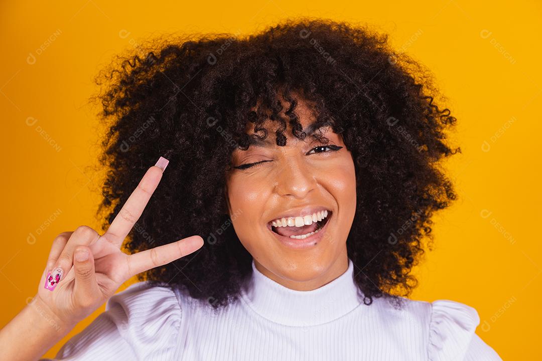 Jovem linda mulher afro-americana com cabelos cacheados, vestindo camiseta casual em pé sorrindo para a câmera
