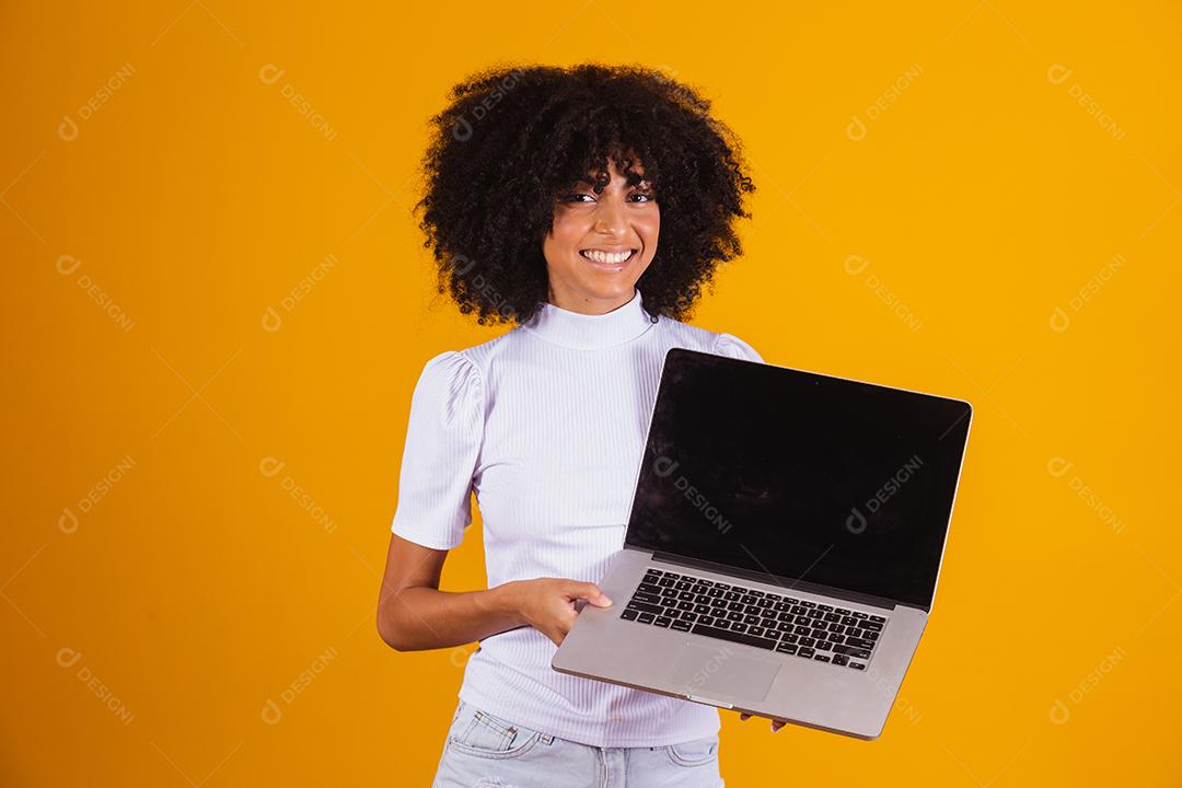 Mulher negra segurando um computador com tela preta