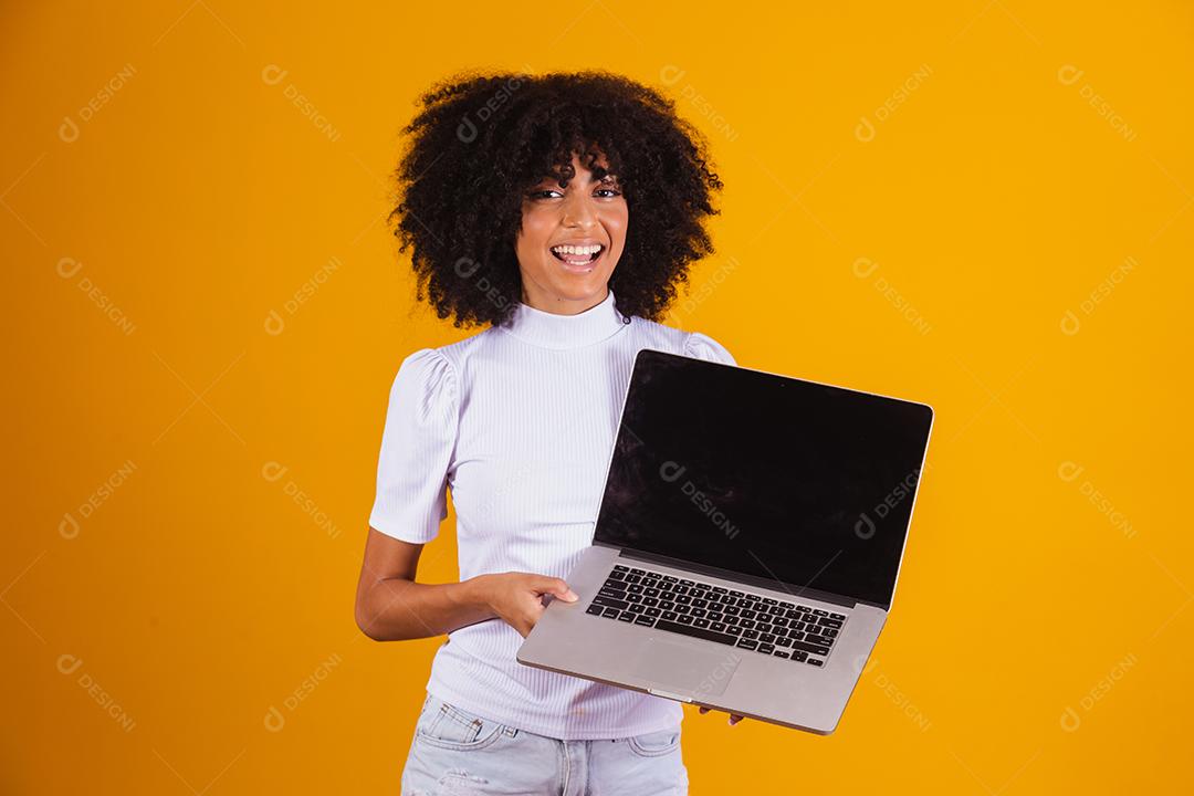 Mulher negra segurando um computador com tela preta