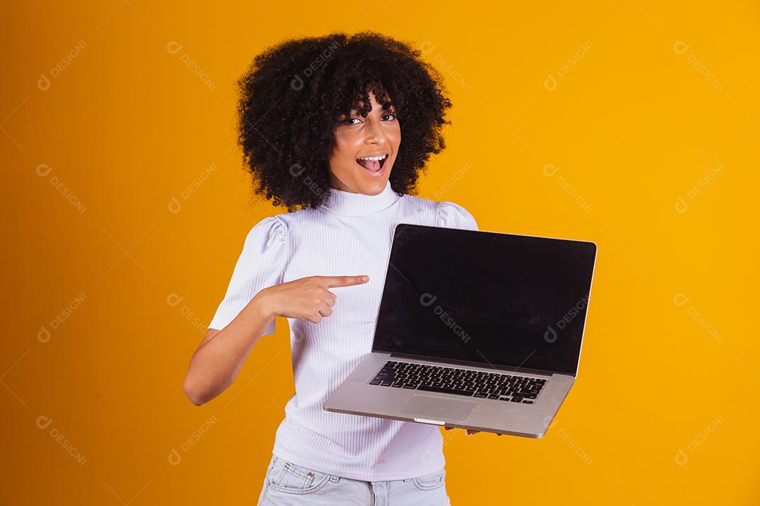 Mulher negra segurando um computador com tela preta