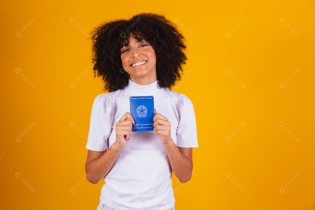 Jovem mulher afro segurando um cartão de trabalho brasileiro. Reforma trabalhista, fgts, salário e conceito de trabalhador formal