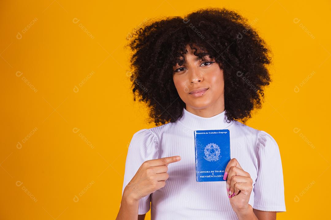 Jovem mulher afro segurando um cartão de trabalho brasileiro. Reforma trabalhista, fgts, salário e conceito de trabalhador formal