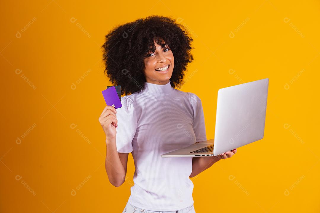 Foto de linda mulher de pele escura animada segurando cartão de crédito plástico mostrando novo modelo de telefone