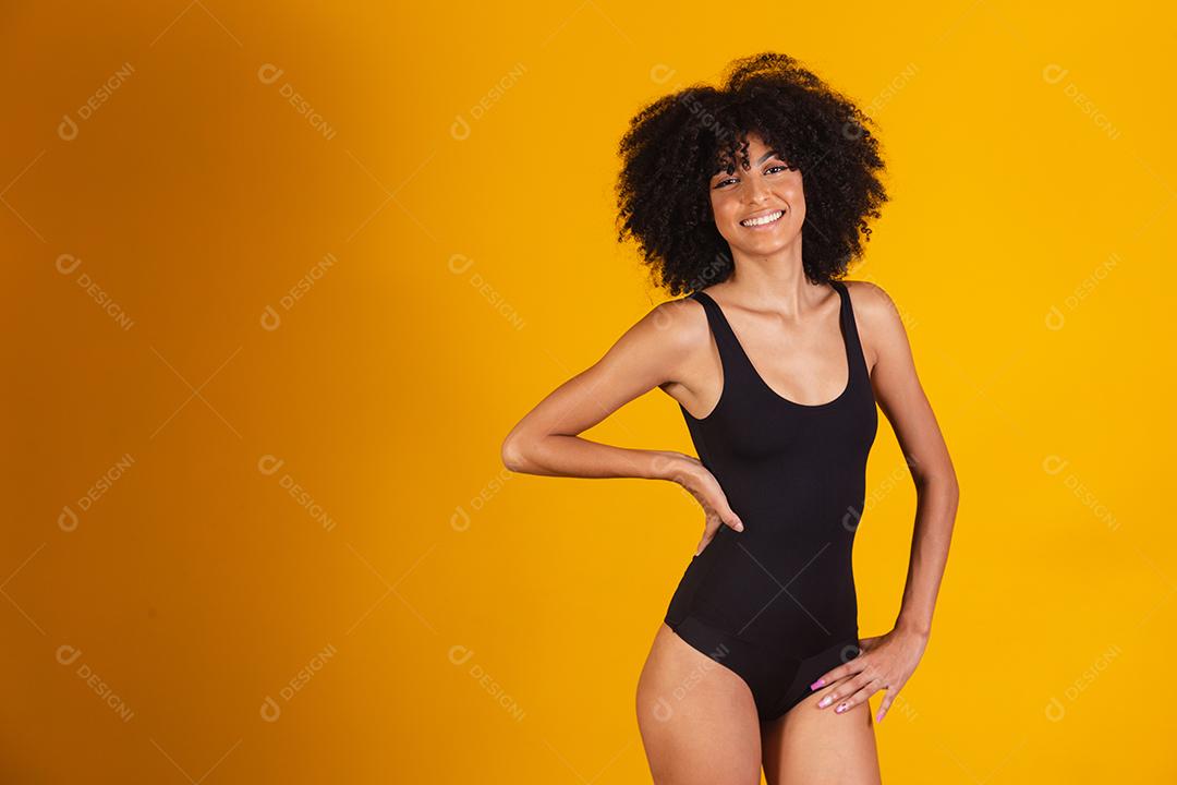 Mulher bonita com cabelo afro em traje de banho em fundo amarelo