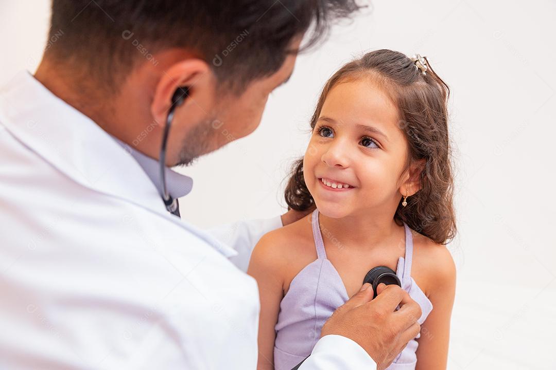 médico atencioso examinando uma garota Doutor examinando pulmão e coração de garotinha