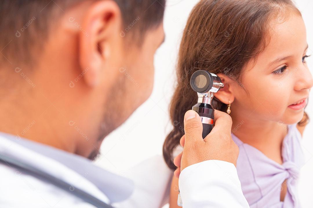 Médico examina a orelha com otoscópio em uma sala de pediatra. Equipamento médico