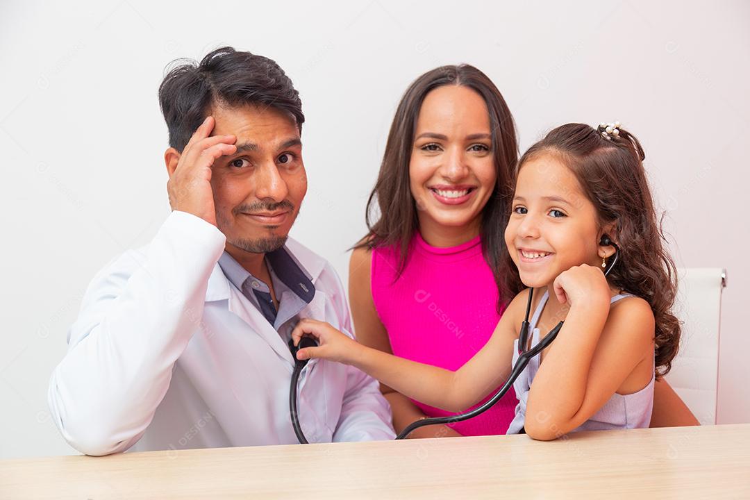 adorável menina em pediatria brincando de ouvir o coração. Criança se diverte ouvindo sua oração com estetoscópio do médico