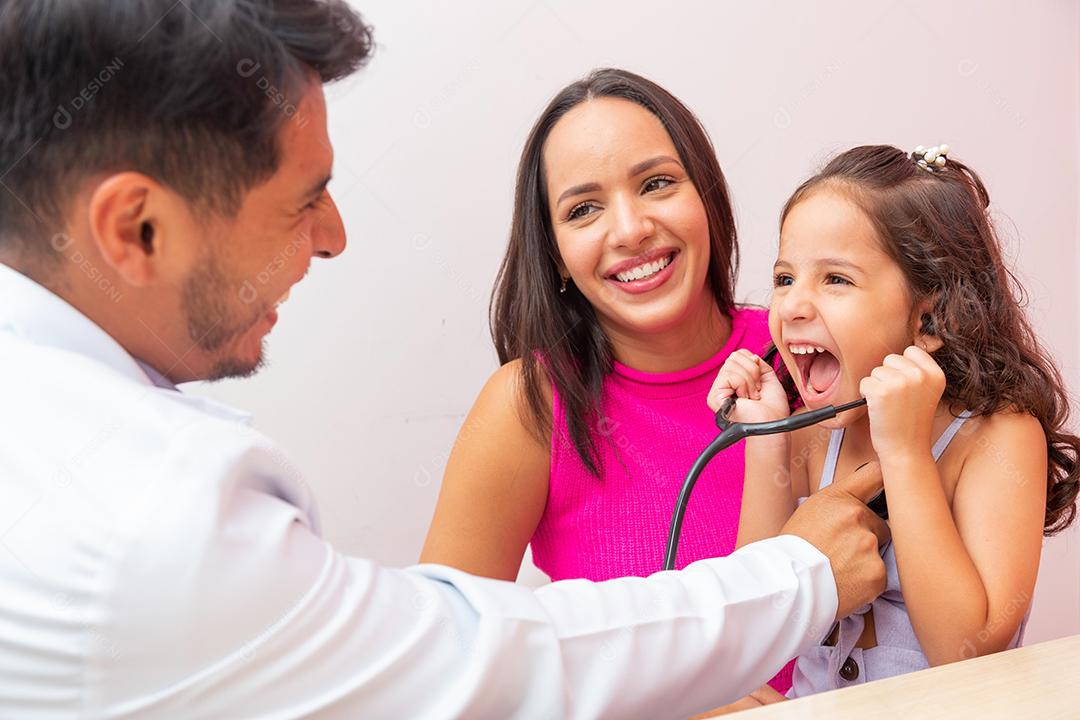 adorável menina em pediatria brincando de ouvir o coração. Criança se diverte ouvindo sua oração com estetoscópio do médico