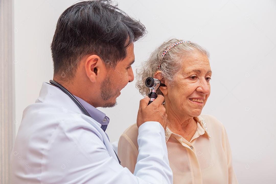 Médico examinando orelha de mulher idosa com otoscópio na clínica