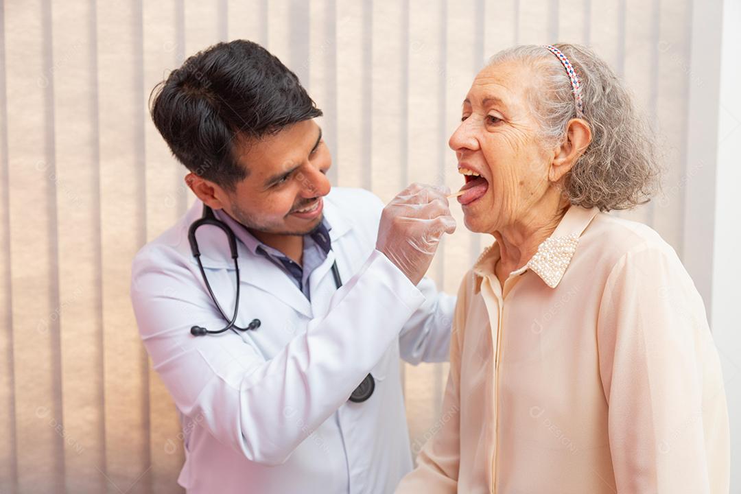 médico masculino examinando a garganta da mulher idosa em consulta.