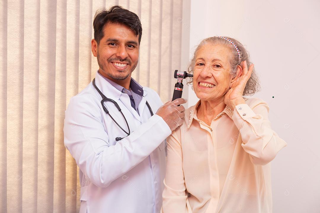 Médico examinando orelha de mulher idosa com otoscópio na clínica