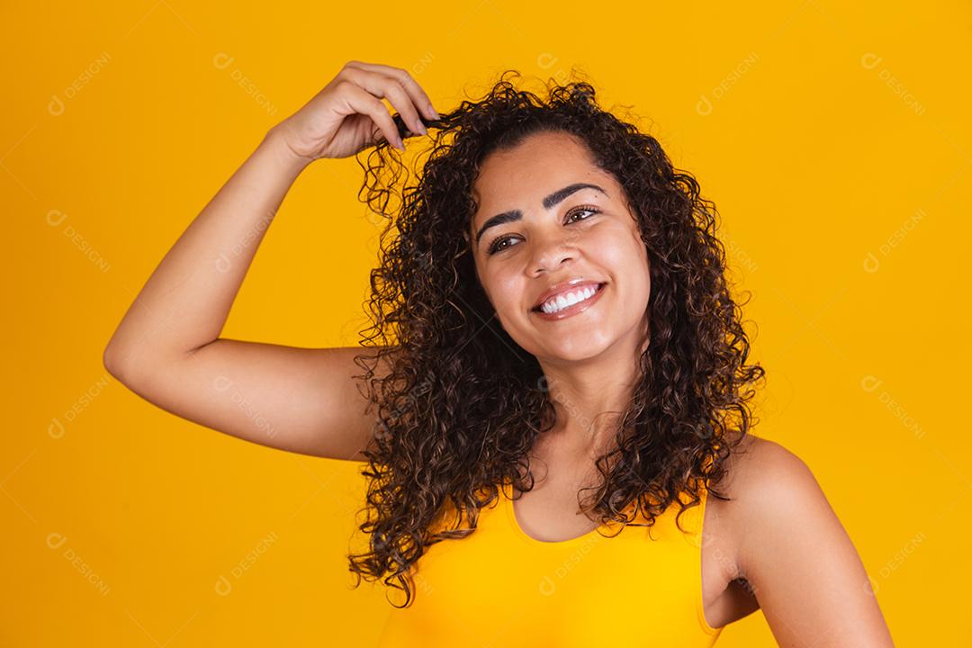 Feliz rindo mulher afro-americana com seu cabelo encaracolado em fundo amarelo. Rindo mulher encaracolada