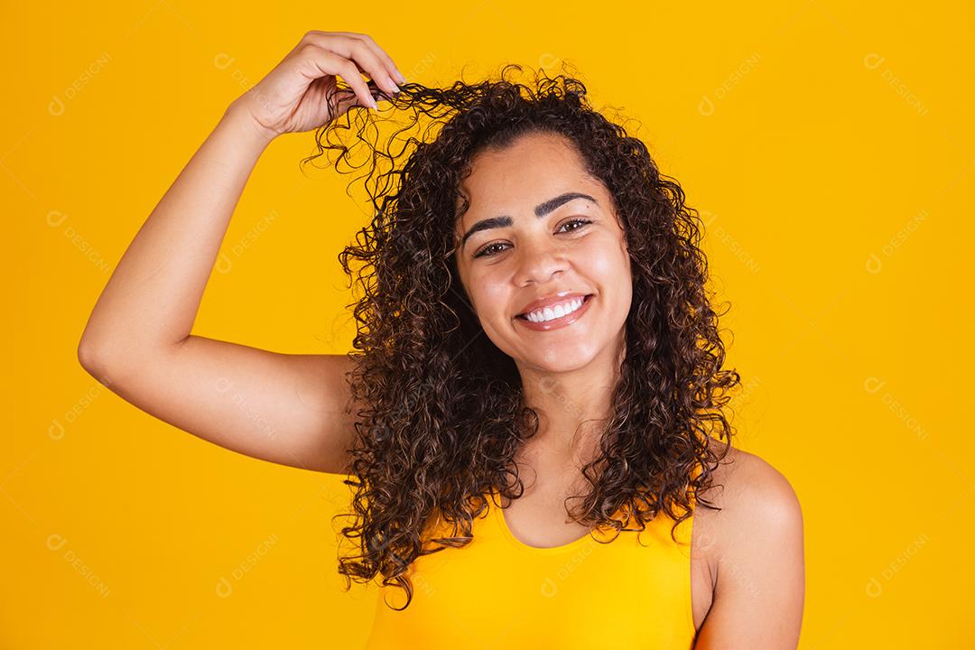 Feliz rindo mulher afro-americana com seu cabelo encaracolado em fundo amarelo. Rindo mulher encaracolada