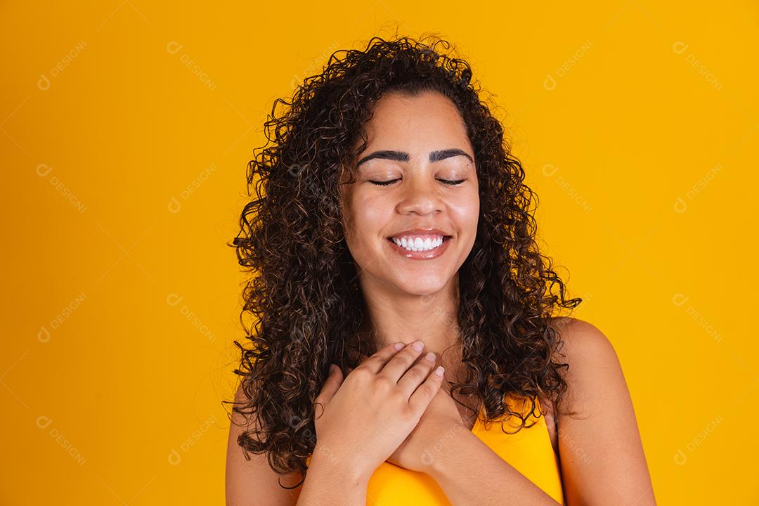 Feliz rindo mulher afro-americana com seu cabelo encaracolado em fundo amarelo. Rindo mulher encaracolada