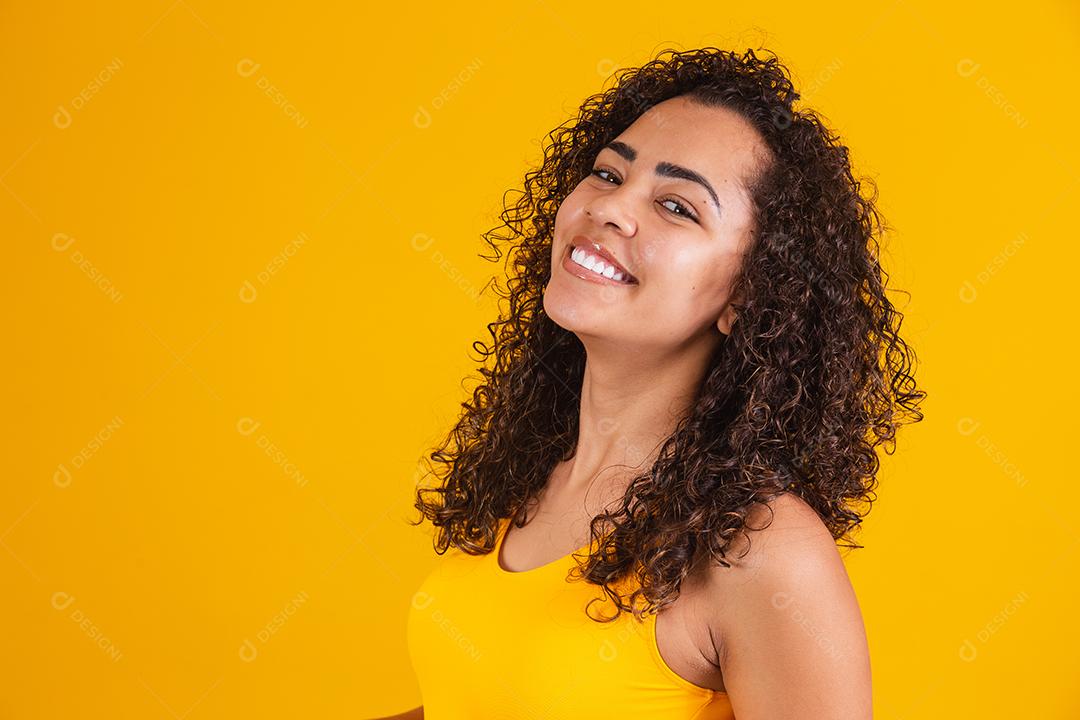 Mulher afro-americana com penteado afro e maquiagem glamourosa. Fundo amarelo.