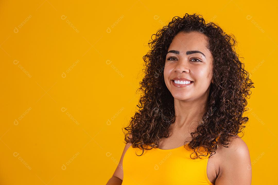 Mulher afro-americana com penteado afro e maquiagem glamourosa. Fundo amarelo.