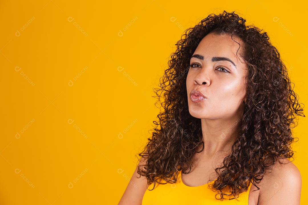 Mulher afro-americana com penteado afro e maquiagem glamourosa. Fundo amarelo.