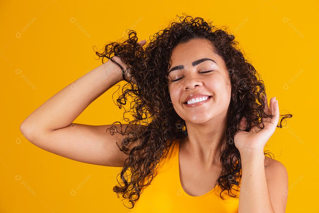 Feliz rindo mulher afro-americana com seu cabelo encaracolado em fundo amarelo. Rindo mulher encaracolada