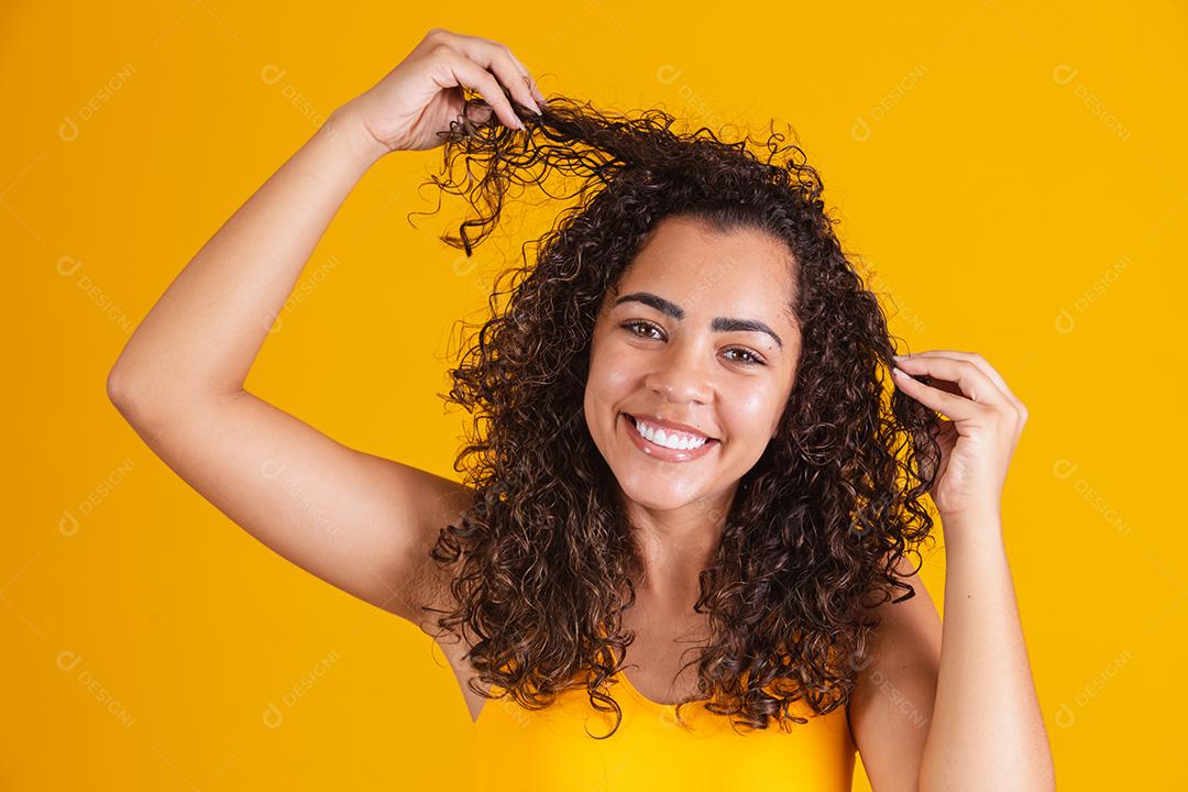 Feliz rindo mulher afro-americana com seu cabelo encaracolado em fundo amarelo. Rindo mulher encaracolada
