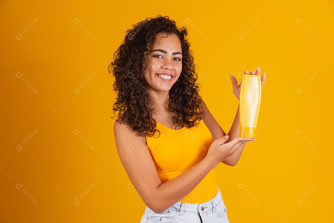 Linda mulher afro segurando um pacote de produtos de cabelo nas mãos dela.