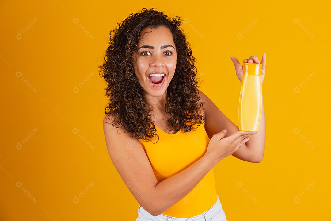 Linda mulher afro segurando um pacote de produtos de cabelo nas mãos dela.