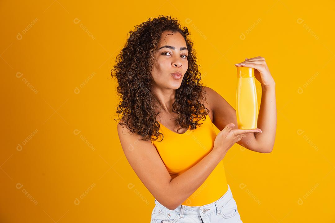 Linda mulher afro segurando um pacote de produtos de cabelo nas mãos dela.