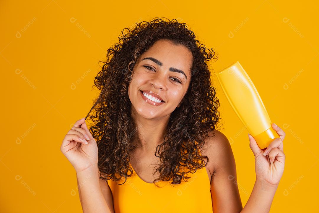 Linda mulher afro segurando um pacote de produtos de cabelo nas mãos dela.