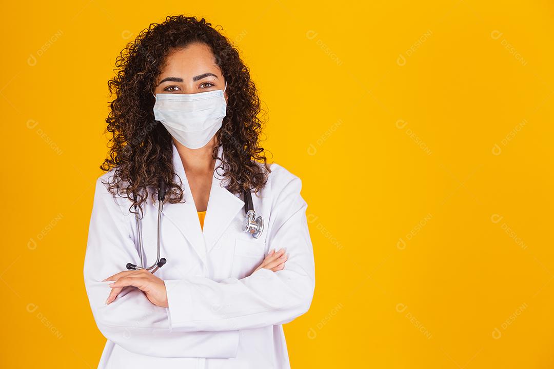 médico de jaleco branco usando máscara cirúrgica com os braços cruzados