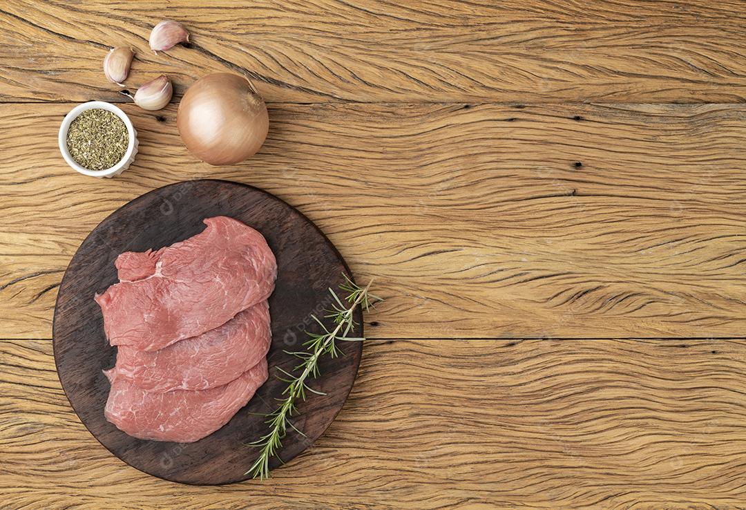 Carne de bife de alcatra sobre tábua de madeira com temperos