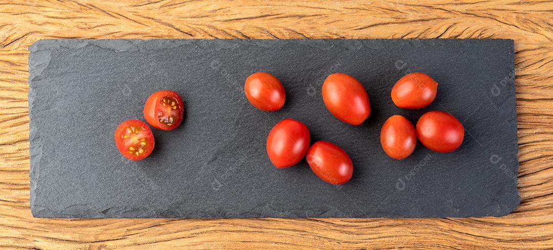 Um grupo de tomates cereja em uma placa de pedra.