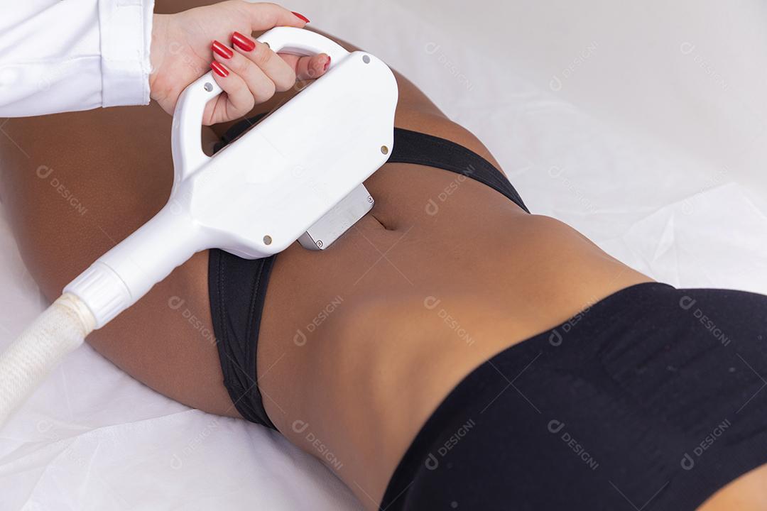 Mulher negra brasileira realizando depilação a laser no abdômen, barriga