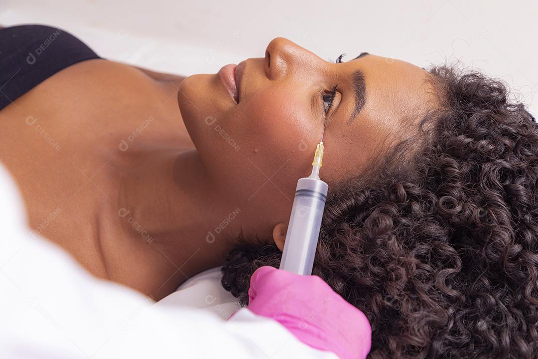 Mulher aplicando ozônio no rosto para tratamento cosmético.