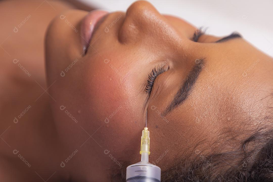 Mulher aplicando ozônio no rosto para tratamento cosmético.