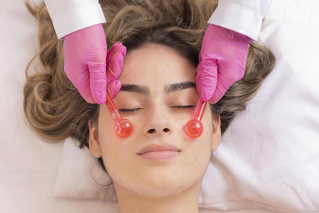 mulher deitada em maca em clinica de estética procedimento de massagem e relaxamento facial